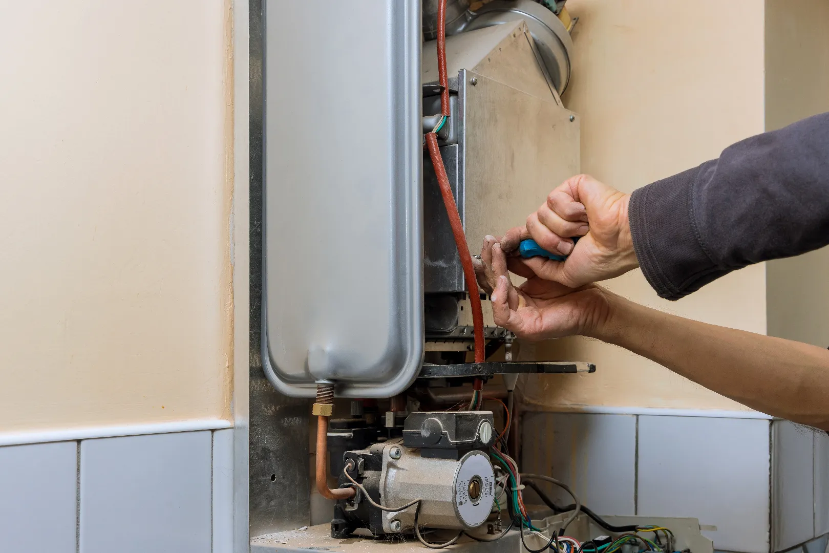 Professional plumber servicing central heating water heater in Burlington home