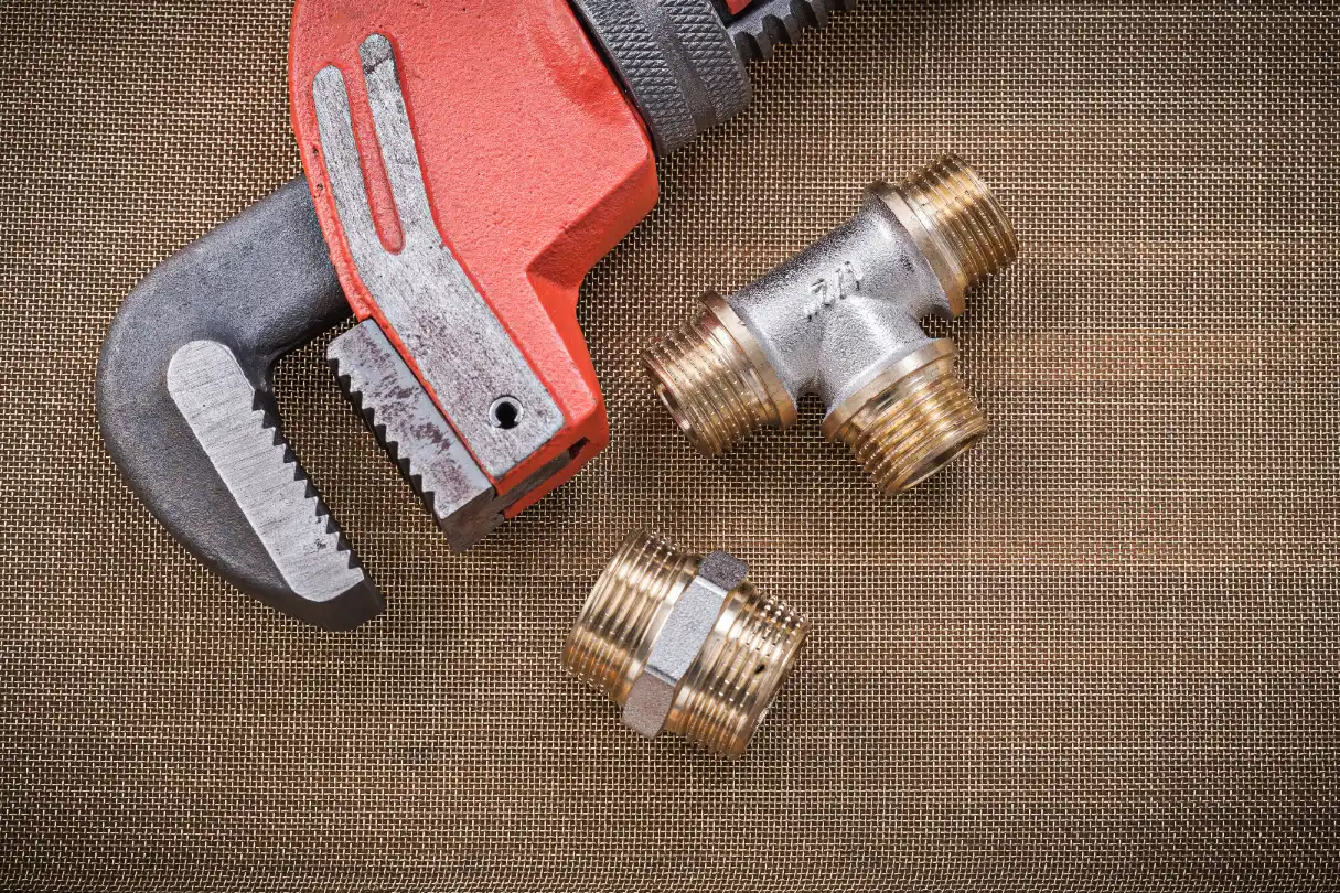 Plumber with wrench and brass plumbing fixtures during pipe repair in Etobicoke