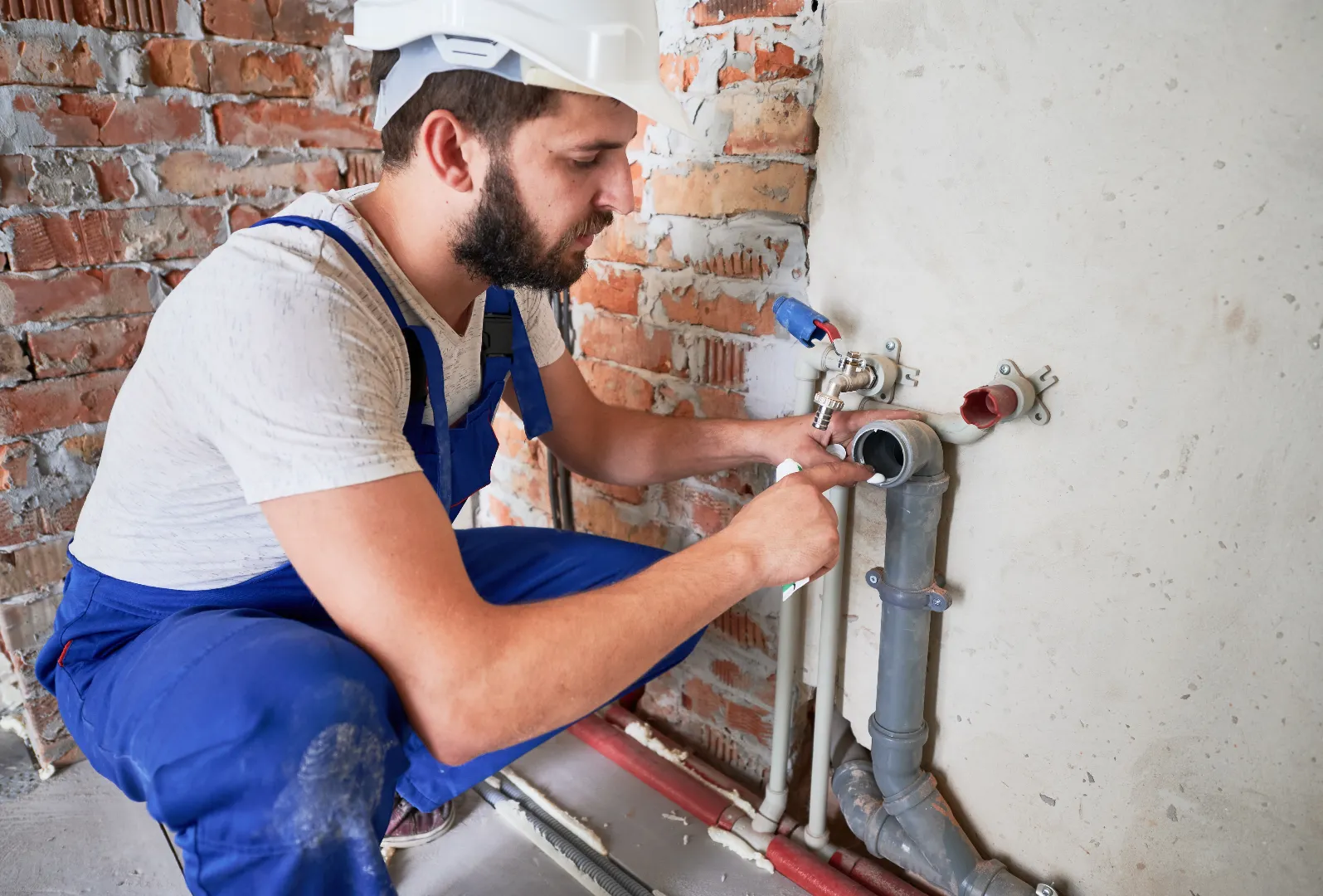 Young plumber working with sealant to fix sewer pipe in Toronto — Emergency Repair Plumbers