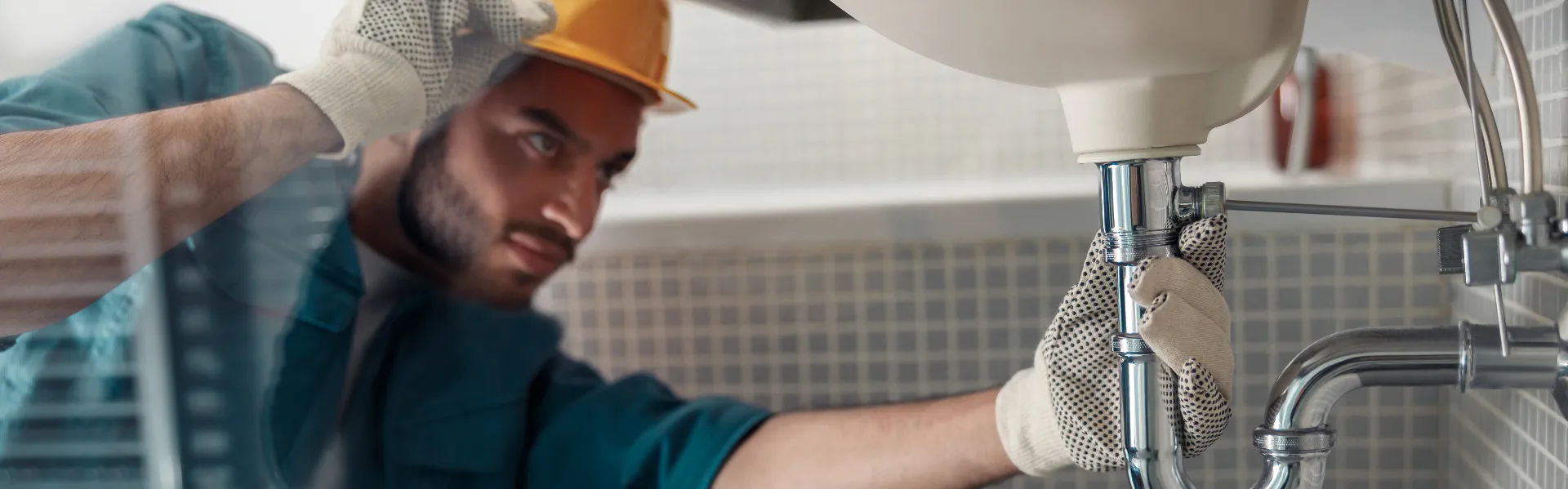 Male plumber repairing bathroom drain and faucet in Vaughan home — emergency repair service