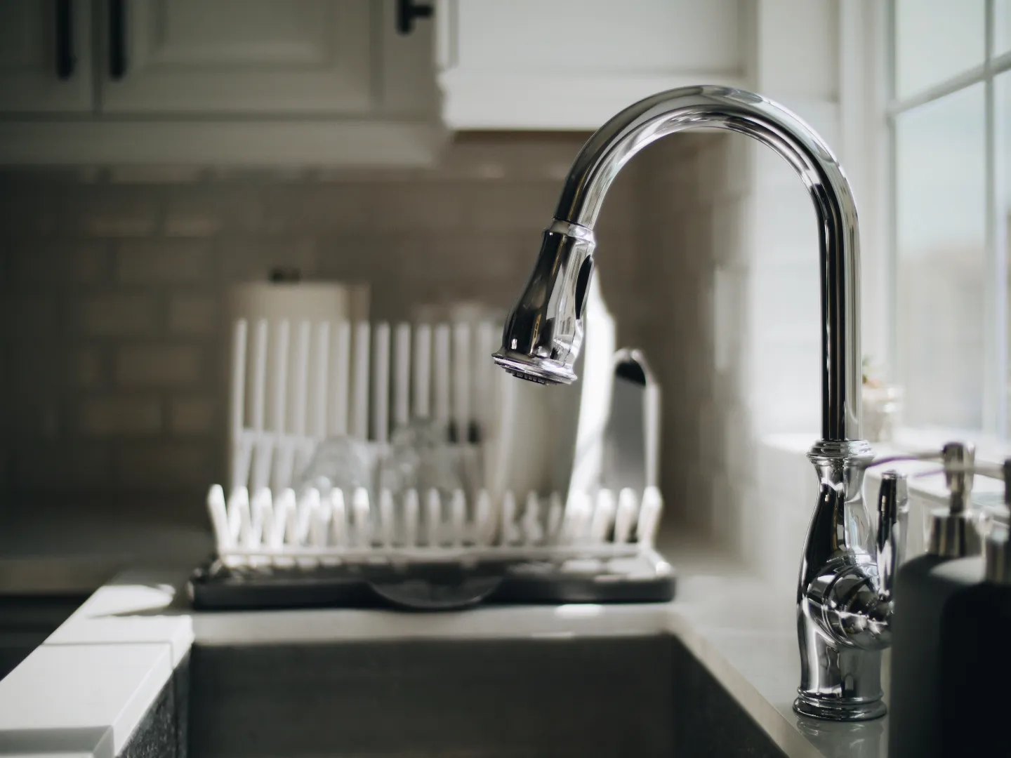 Grey kitchen sink with shiny chrome faucet being repaired by Toronto plumber